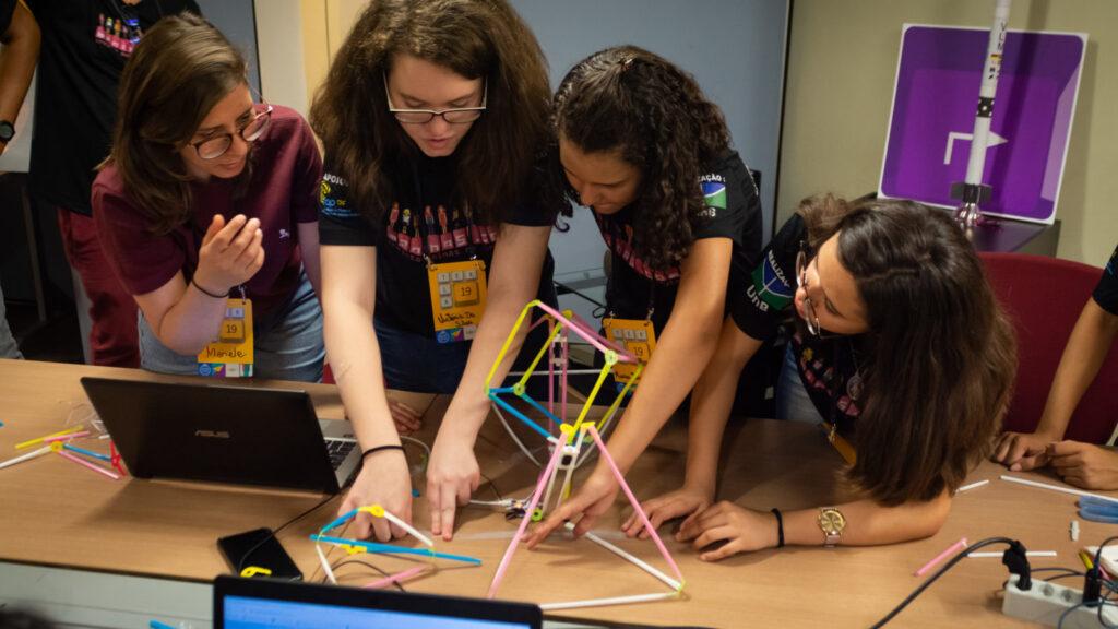 Young women building a structure together.