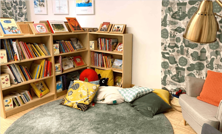 A cosy corner with pillows and a bookshelf with children's literature