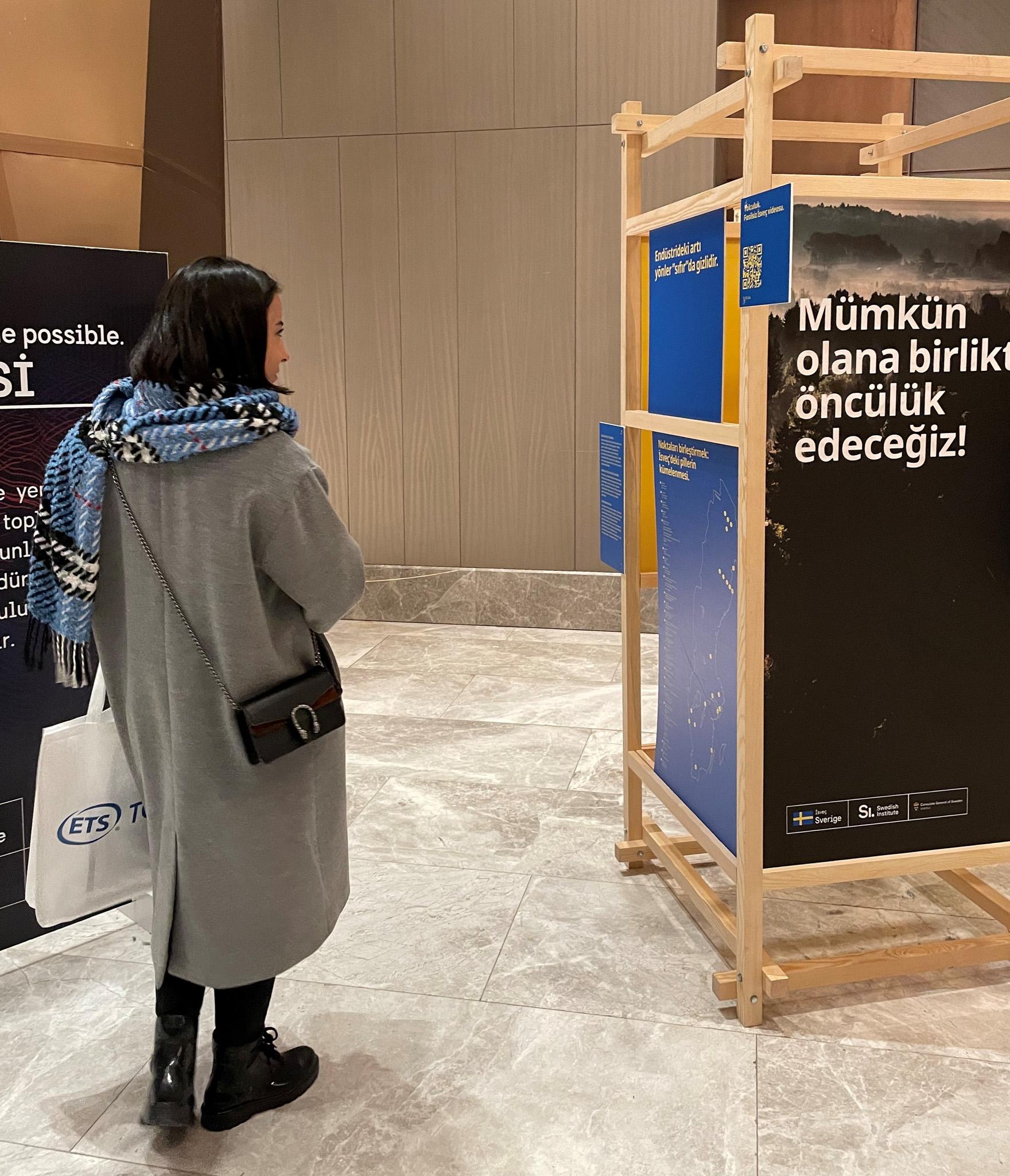 A young woman reading the exhibition text in Turkish.