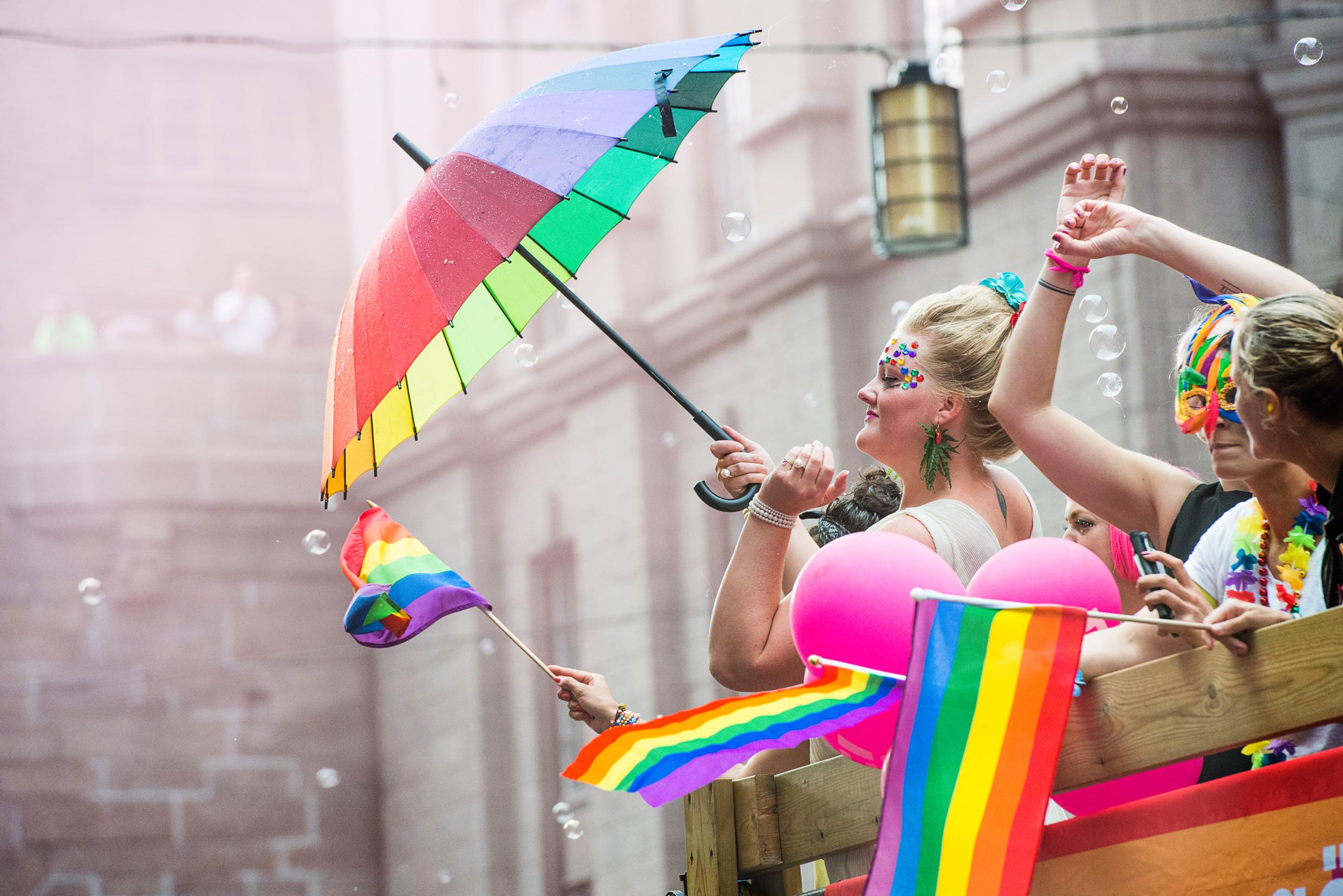 A woman with a rainbow umbrella at a Pride Parade.