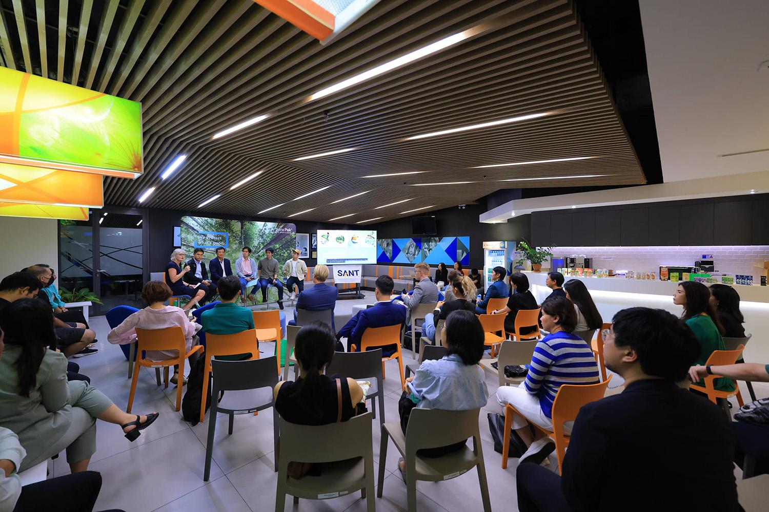 A panel discussion watched by an audience in a modern and colorful room.