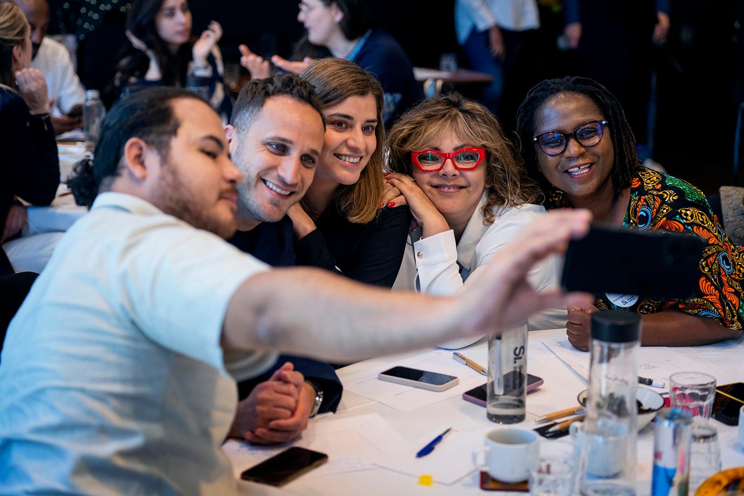 A group of alumni from different countries take a photo together at an event.