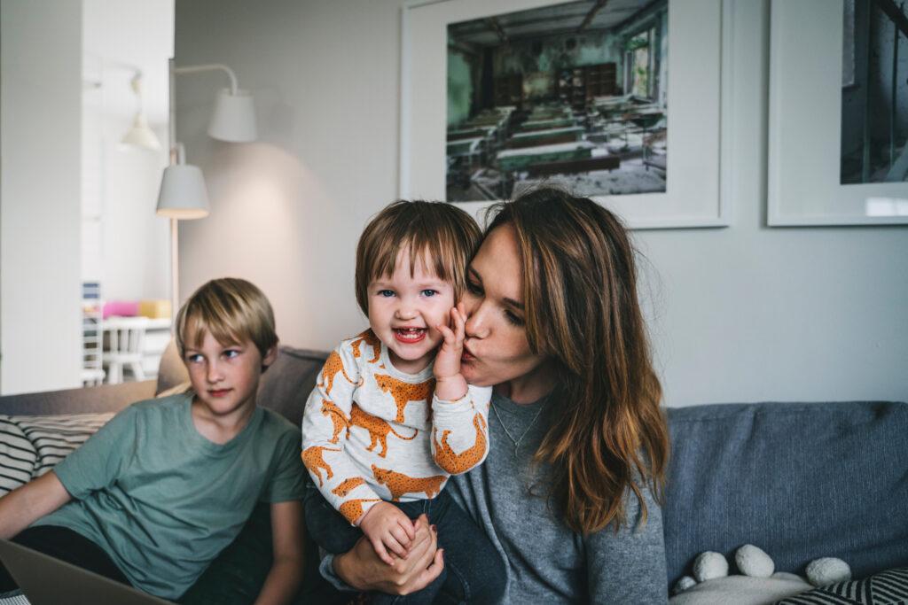 Family setting with a mother and children sitting on a sofa.