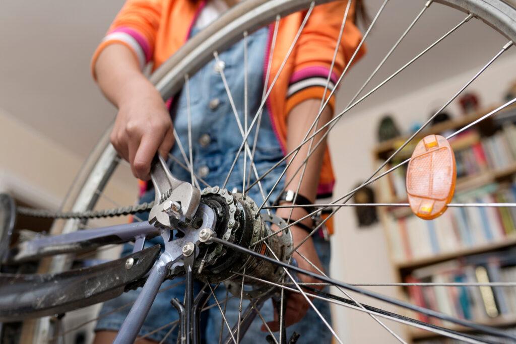 Close-up of a hand using a wrench to fix a bicycle wheel.