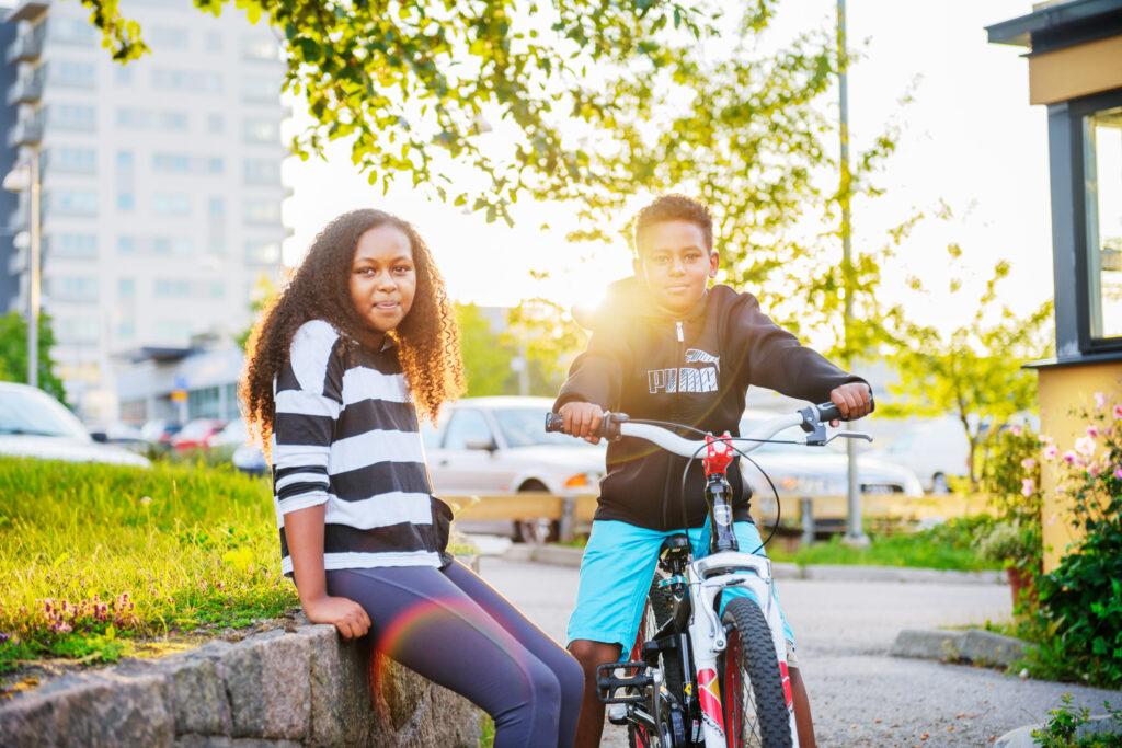 Two siblings in a Swedish suburb getting home from school by bike.