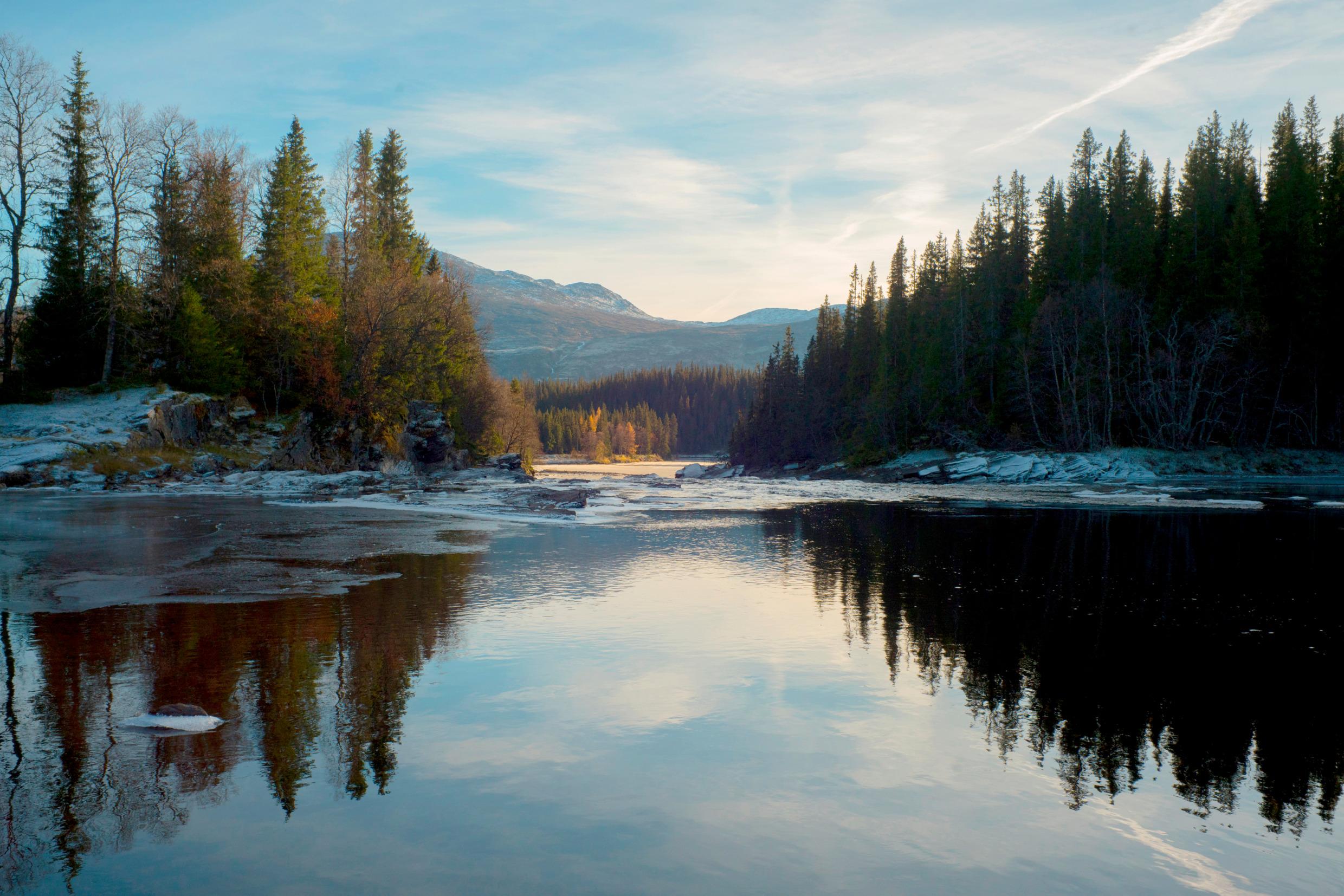 Still water surrounded by forest and mountains in the autumn in Sweden.