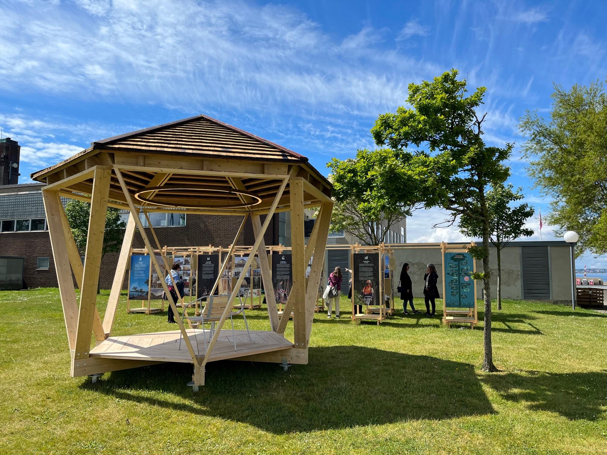 A wood pavilion and the exhibition on a green lawn. 