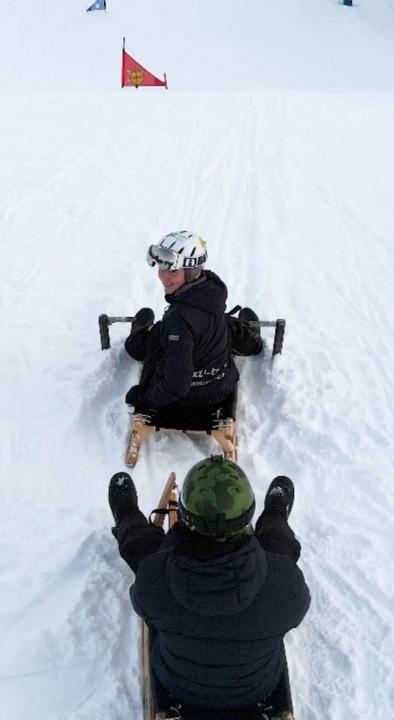 Two girls on wooden sledges.