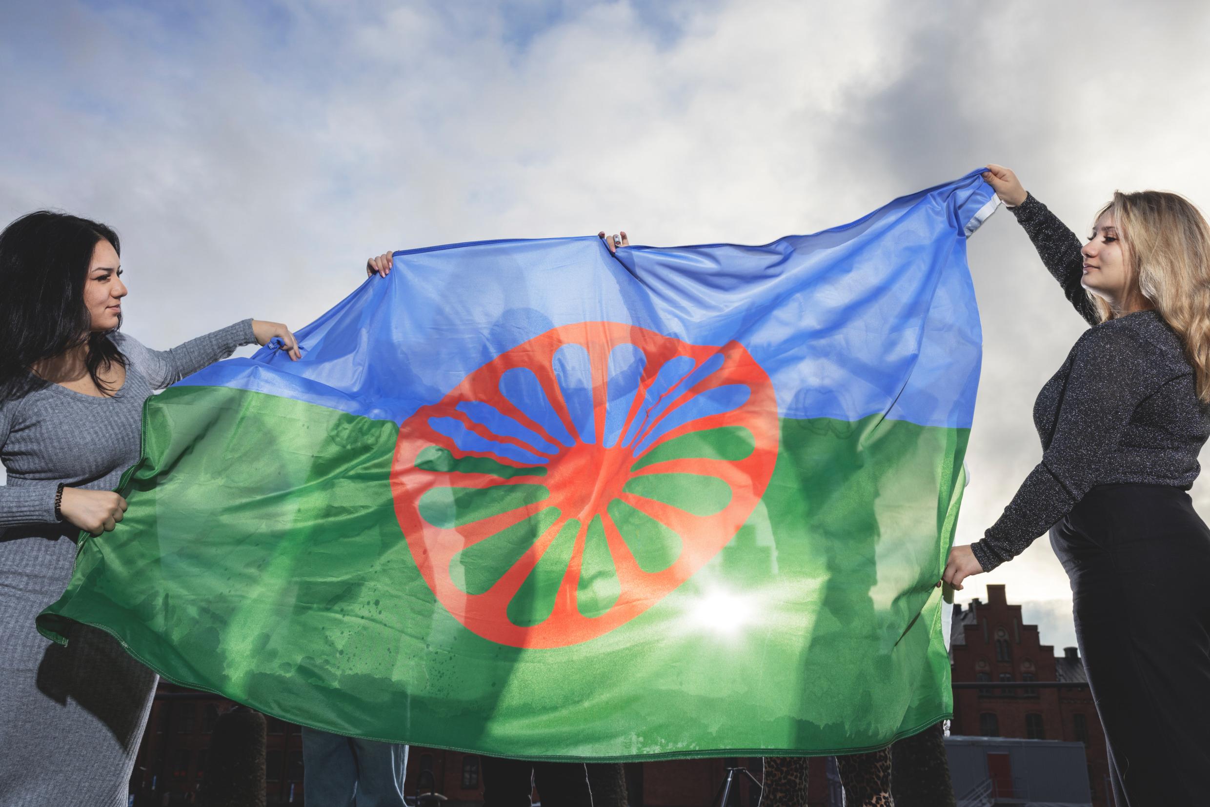 Two women holding a Roma flag.