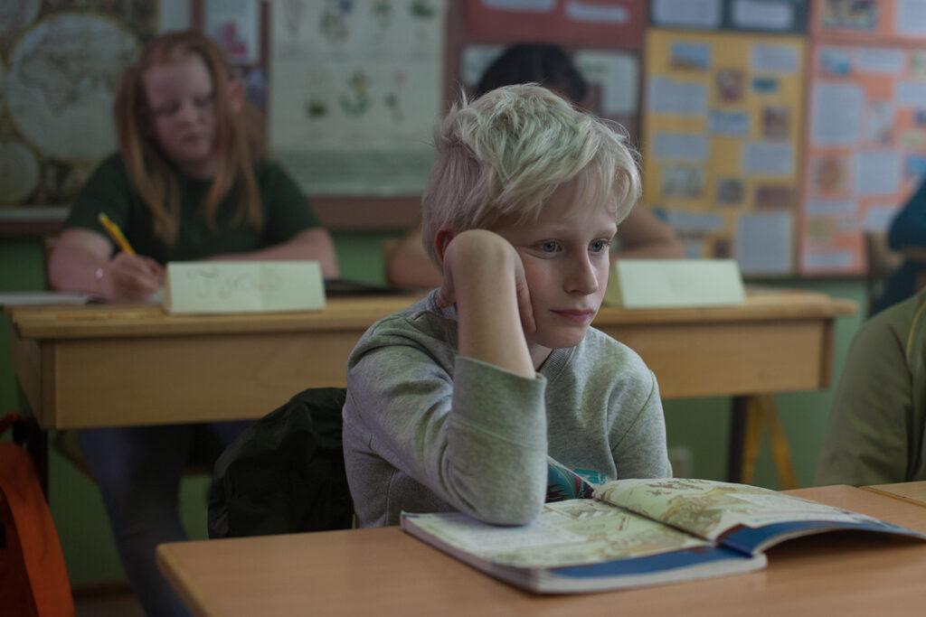 A boy looking troubled in a classroom.