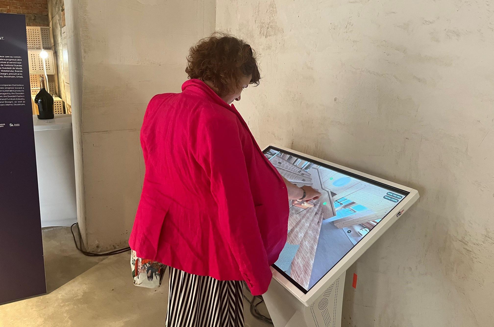 A woman in a red blazer using a touch screen.