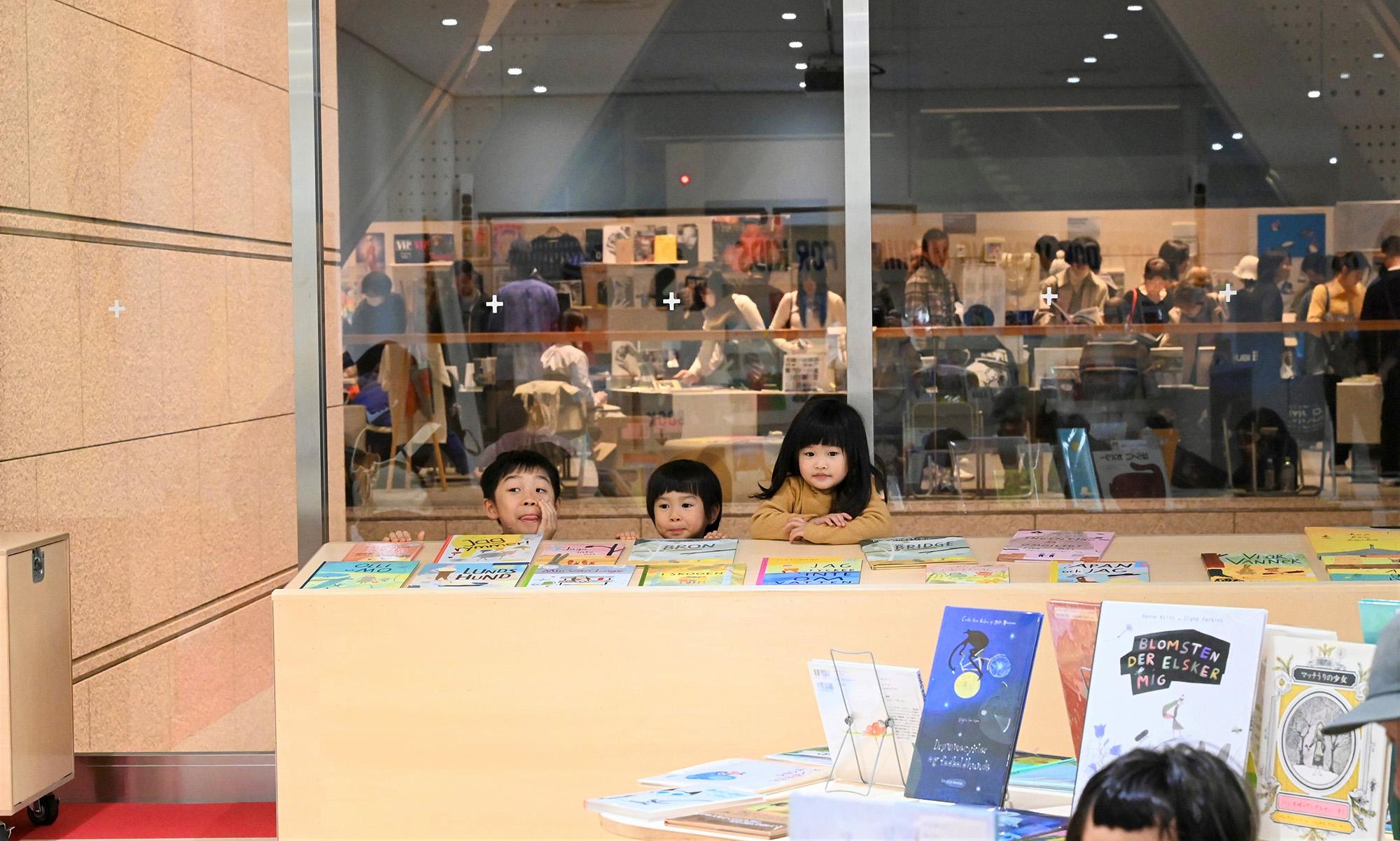 Children from Tokyo playing around bookshelves.