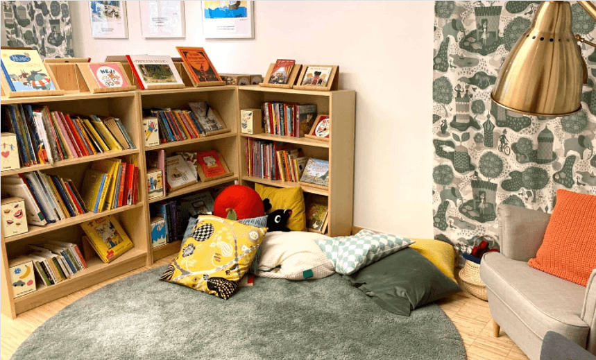 Little library with play furniture, carpets and cosy pillows.
