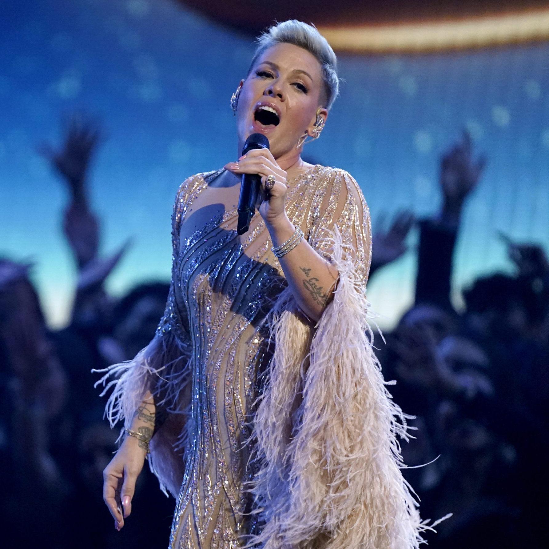 Pop artist Pink performing, with an audience seen in the background.