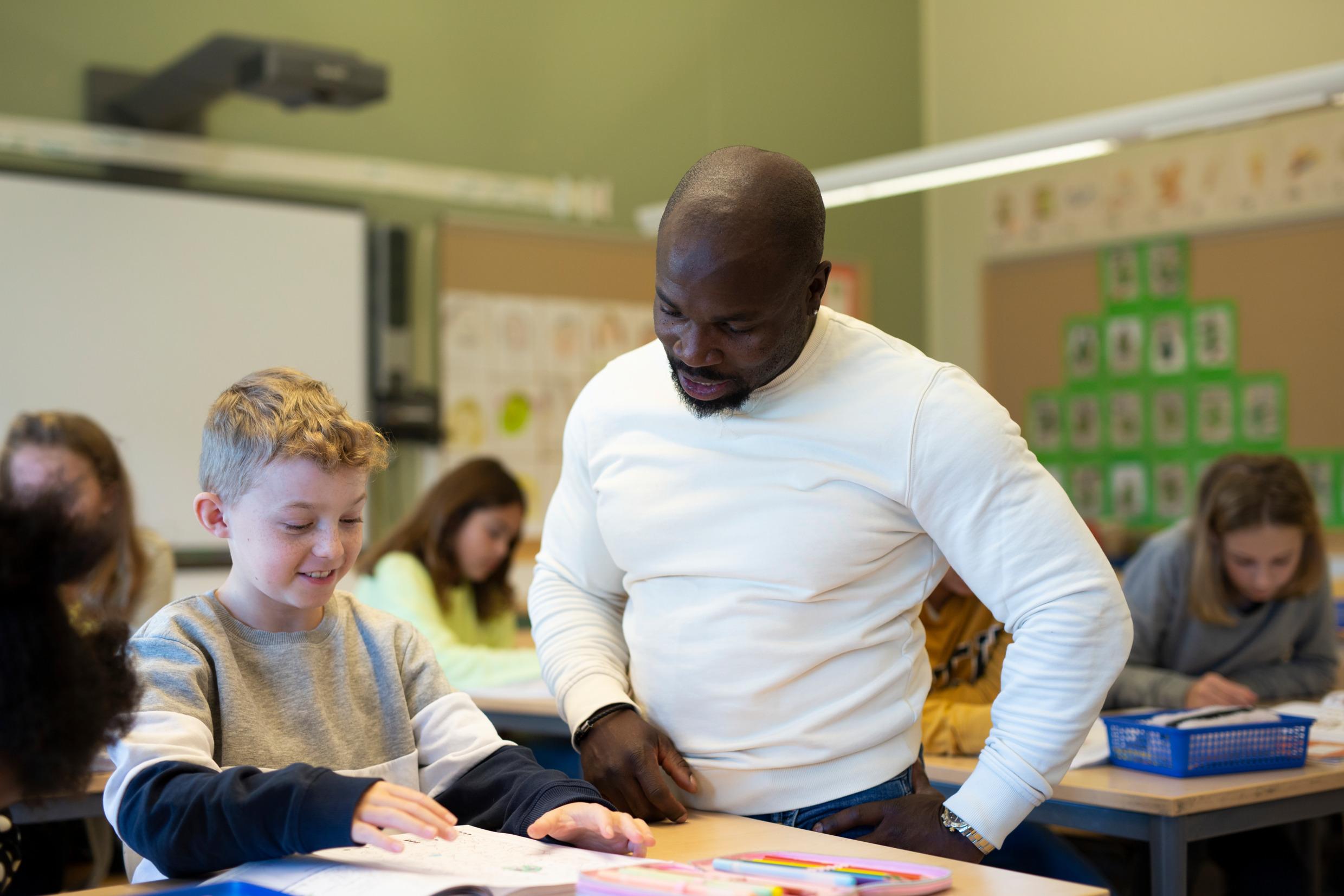 A teacher helping a schoolchild in the classroom.