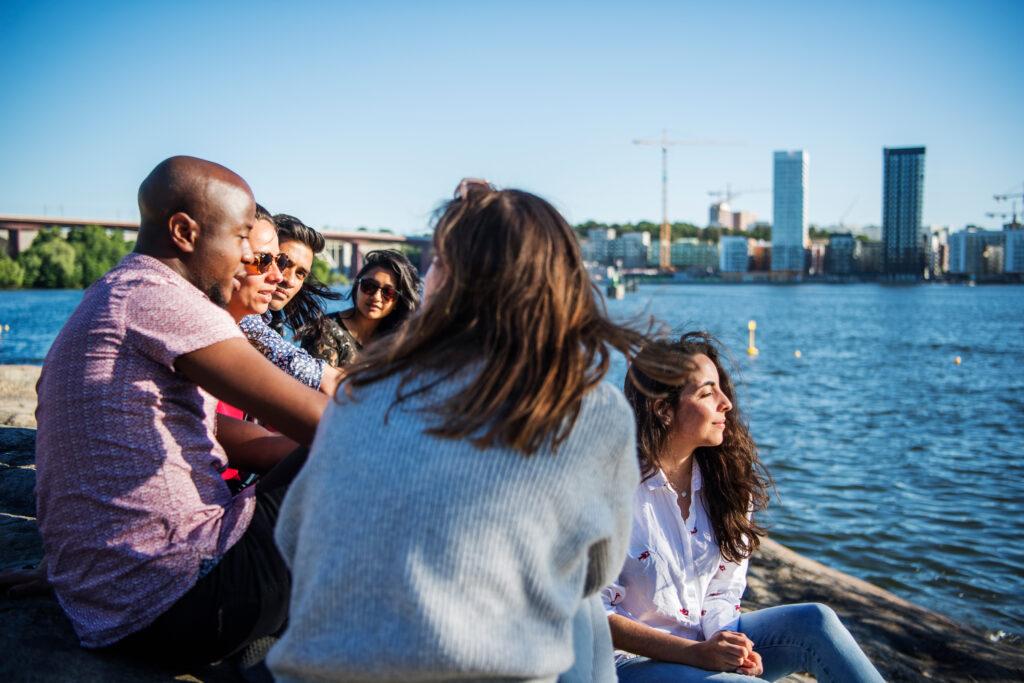 A group of friends sitting enjoying the sun by the water front in Stockholm.