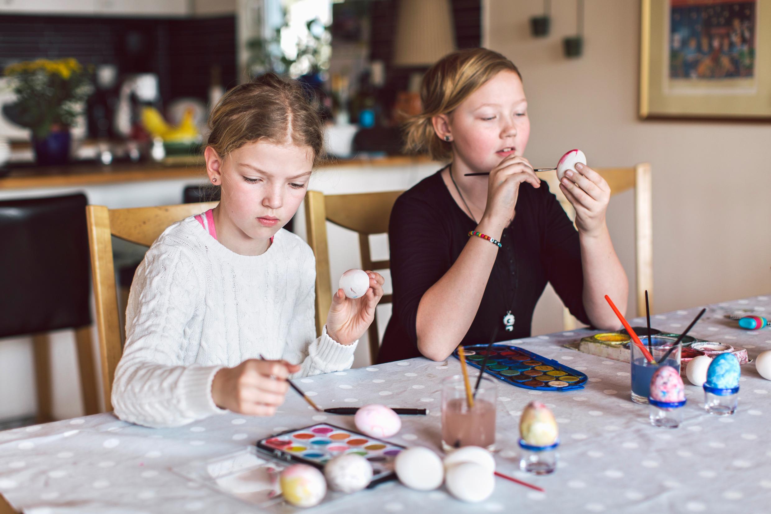 Two children paint on boiled eggs.