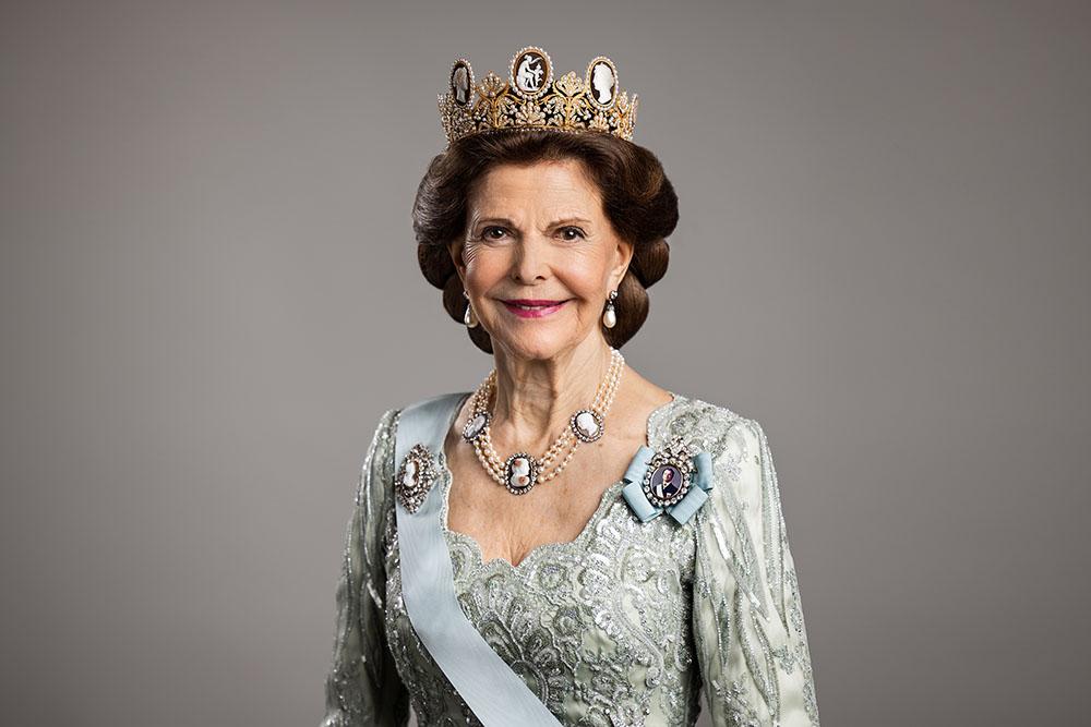 Queen Silvia in a blue dress and tiara.