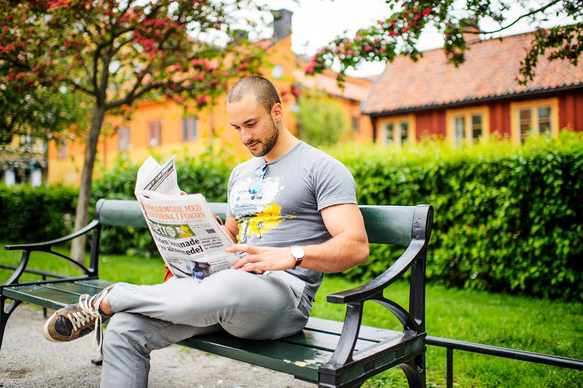 A person reading the newspaper in a park,