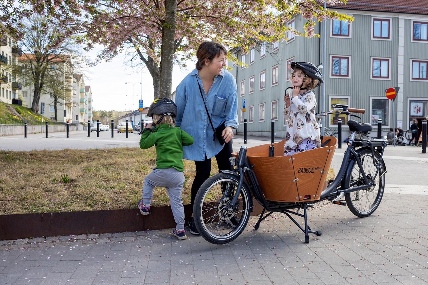 A parent and two children with a cargo bike.