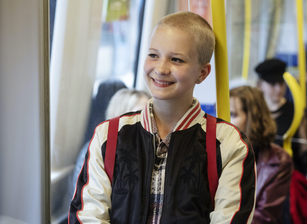 A teenaged girl with a shaved head in the subway.