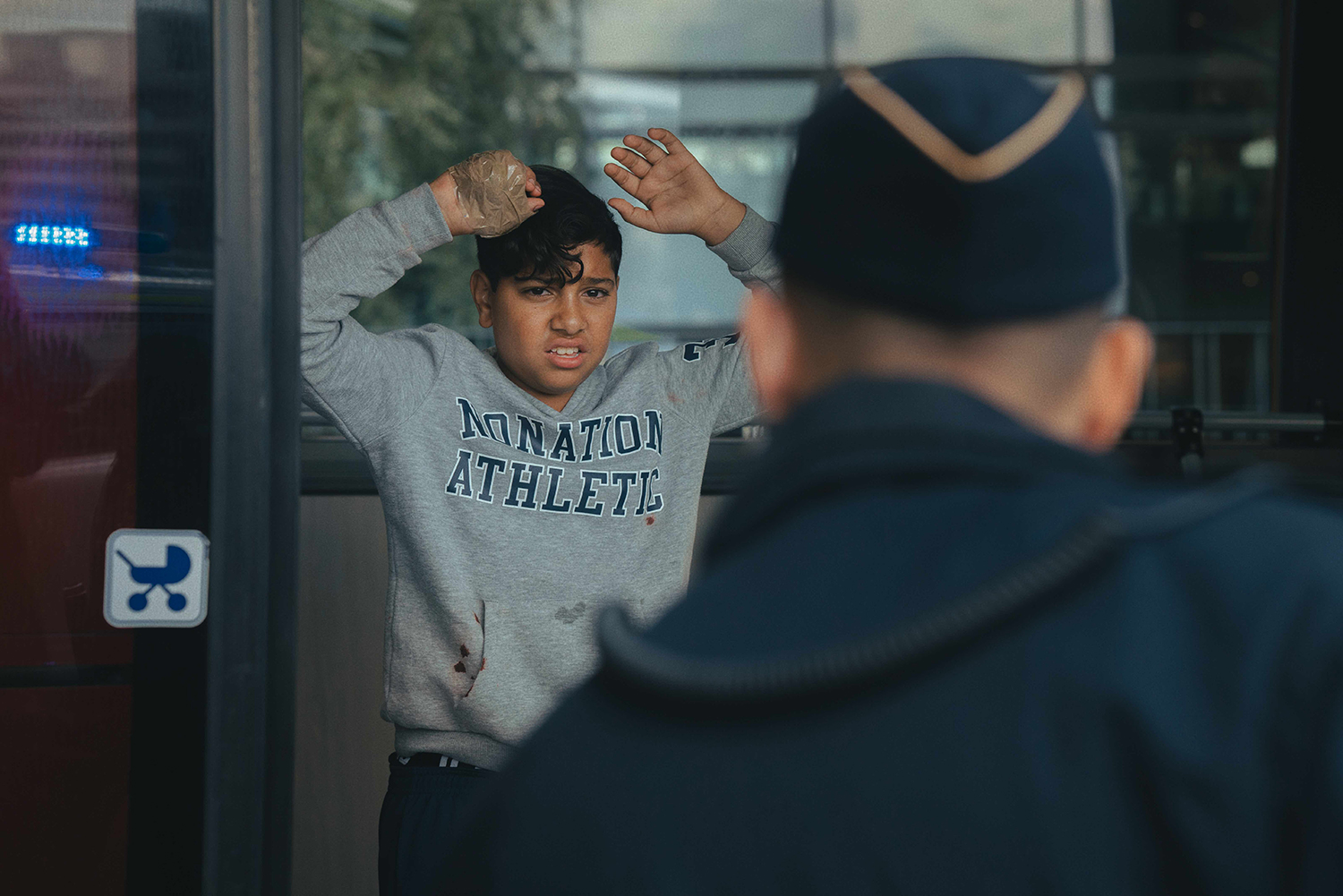 Abdel holding up his hands in front of the police, traces of blood on his sweater and something taped to his hand.