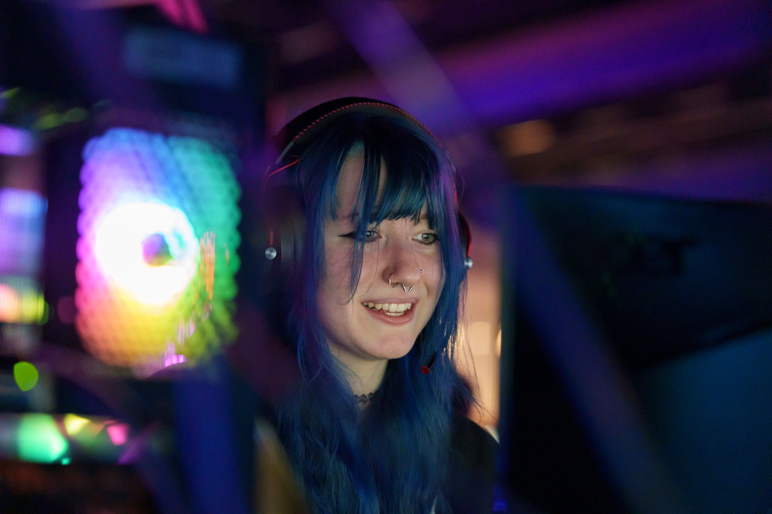 A girl with blue hair sitting in front of a computer screen.